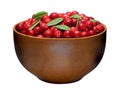 One full wooden bowl of the red berries and its green leaves is isolated on the white background