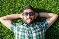 One funny fashion middle eastern man with beard and fashion hair style is resting on beautiful green grass day time. Royalty Free Stock Photo