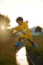 One giant leap for boykind. a little boy jumping over some water while playing outside. Royalty Free Stock Photo