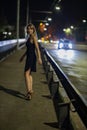 One girl in black dress and on heels turned back  at night. She goes quickly on the road. Picture has dark  tones. Royalty Free Stock Photo