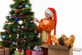 One girl hangs a ball on the Christmas tree, the other climbed into the box with her head