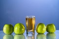 One glass of apple juice with green apples in the beautiful bluebackground. Reflected surface. Summer day. Good mood. Royalty Free Stock Photo