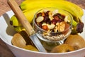 One glass bowl of mixed nuts , Three bananas and four kiwi fruit in white bowl