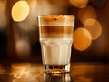 One glass cup of coffee latte macchiato with cinnamon-sprinkled foam on the table in the cafe. Blurred background