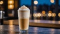 One glass cup of coffee latte macchiato with cinnamon-sprinkled foam on the table in the cafe. Blurred background