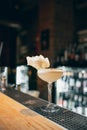 One glass filled with alcohol cocktail or shampagne decorated with cotton candy standing on bar counter