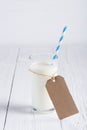 One glass of milk with blue stripped paper straw and blank paper tag on rope