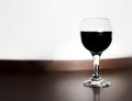 One glass of red wine wooden table and blurred white wall background. Alcohol drink on desk in room. Royalty Free Stock Photo