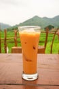One glass of Thai tea on the table with green hills and rice fields in the background Royalty Free Stock Photo