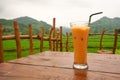 One glass of Thai tea on the table with green hills and rice fields in the background Royalty Free Stock Photo