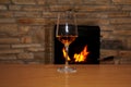 One glass of wine stands on a table in front of a fireplace, in which firewood burns with a bright flame, a concept of a romantic Royalty Free Stock Photo