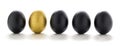 One golden egg among black eggs in a row isolated on white background Royalty Free Stock Photo