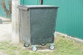 One gray black metal trash can on wheels stands in the grass Royalty Free Stock Photo