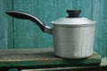 One gray cast-iron saucepan with a black handle stands on a wooden table