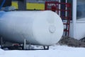 Gray long iron tank at a gas station in the snow