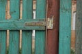 One gray metal door hinge on a brown rusty iron post and green planks Royalty Free Stock Photo