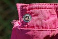 One gray metal rivet button on the pink fabric sleeve