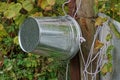 One gray metal zinc bucket hangs on a wooden pole with a white rope near a well Royalty Free Stock Photo