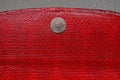 Metallic single rivet button on red leather wallet