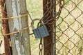 one gray padlock on an brown iron gate