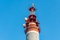 One gray and red Radio relay tower with group of different antennas on the blue sky background