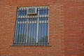 One gray window behind bars on the red brick wall Royalty Free Stock Photo