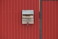 One gray wooden mailbox hanging on a red metal fence wall Royalty Free Stock Photo