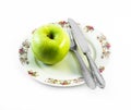 One green apple with knife and fork on a white plate with decorations and white background Royalty Free Stock Photo