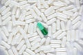 One green dissimilar capsule lie on a white capsules