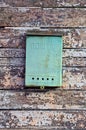 one green metal mailbox hanging from an old worn gray brown wooden fence Royalty Free Stock Photo