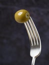 one green olive on a fork isolated on blue background Royalty Free Stock Photo