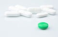 One Green Pill is on the Background of White Pills. Royalty Free Stock Photo