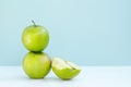 One green Apple on another and next half bitten Apple on blue background