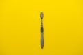 One grey toothbrush for teeth on a yellow background.