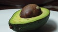 One half of the avocado spining on the white plate