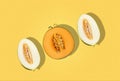 One half of cantaloupe melon and two halves of tendral one in cross-section, on yellow background, copy space for text Royalty Free Stock Photo