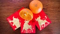 One and a half mandarins, and three golden bull red packets, on wooden background.Chinese new year 2021 year of the ox.