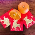 Three golden bull red packets and cumquats, on wooden background. Chinese new year 2021 year of the ox. Square photo image.