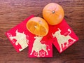 One and a half mandarins, and three golden bull red packets, on wooden background.