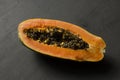 One half of papaya fruit cut in half, lie on black modern background. Black seeds of sweet, orange papaya. Vegetarianism, healthy Royalty Free Stock Photo