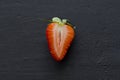 One half of strawberry, cut red beautiful strawberry close-up, on a black dark concrete background. Macro shooting. Fruit erotica