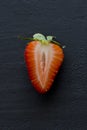 One half of strawberry, cut red beautiful strawberry close-up, on a black dark concrete background. Macro shooting. Fruit erotica