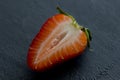 One half of strawberry, cut red beautiful strawberry close-up, on a black dark concrete background. Macro shooting. Fruit erotica