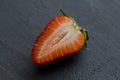 One half of strawberry, cut red beautiful strawberry close-up, on a black dark concrete background. Macro shooting. Fruit erotica Royalty Free Stock Photo