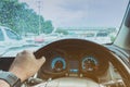One hand of a driver on steering wheel of a car with raindrops on the windscreen in a rainy day. Royalty Free Stock Photo