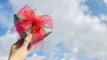 Holding a green gift against a background of blue sky and white clouds. Royalty Free Stock Photo