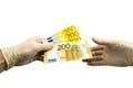 One hand in white protective gloves holds out a bundle of 200 two hundred euro bills to the other hand in a white medical glove. Royalty Free Stock Photo