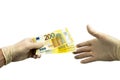 One hand in white protective gloves holds out a bundle of 200 two hundred euro bills to the other hand in a white medical glove. I Royalty Free Stock Photo