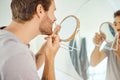 One handsome man checking his teeth in a bathroom at home. Caucasian male cleaning his teeth and looking in a mirror in Royalty Free Stock Photo