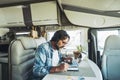 One handsome mid age man working on mobile cell phone and laptop computer inside a camper van sitting at the table. Modern online Royalty Free Stock Photo